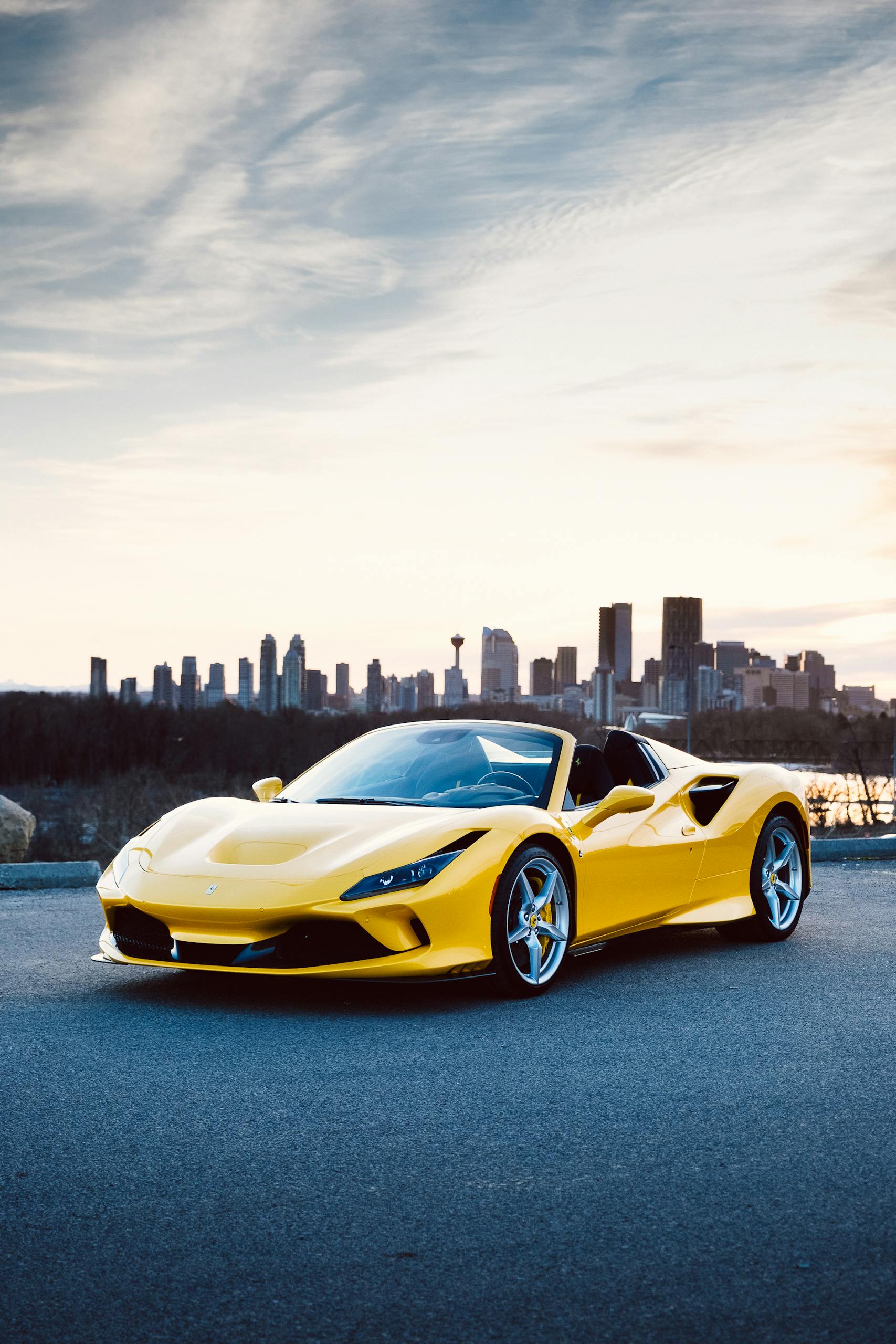 Striking yellow sports car parked with a city skyline at dusk.